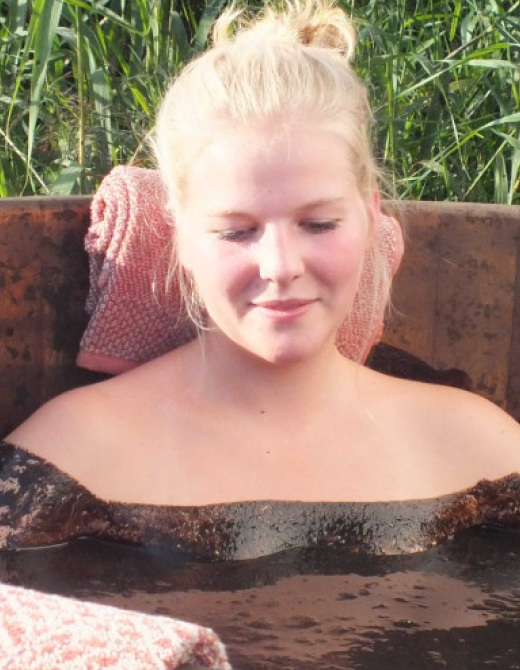 Frau entspannt im warmen Wasser eines Heilbads im Freien.