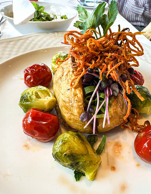 Angerichtetes Gericht mit Gemüse, Kräutern und Beilage auf einem Teller.